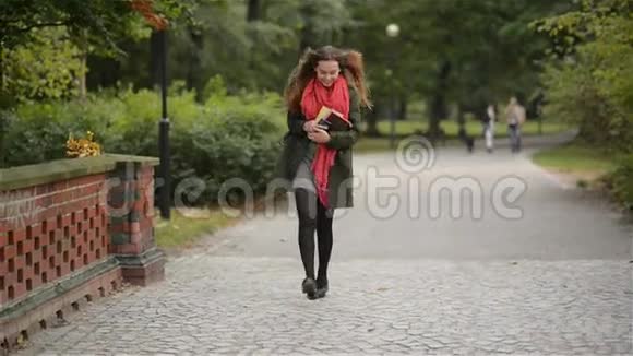 美丽的美丽的快乐女子走在秋天的公园里学生女孩在电话上交谈在一个微笑上视频的预览图