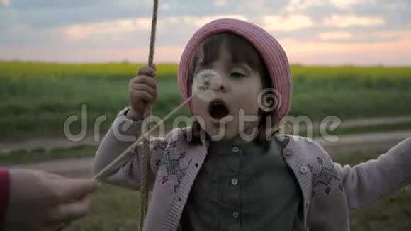 肖像女孩子吹在吹球花可爱的女孩吹蒲公英慢动作快乐的孩子在视频的预览图
