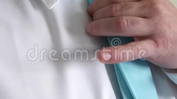 一个商人早上去上班时用双手系着蓝色的领带系着白色衬衫企业雇员的概念视频的预览图