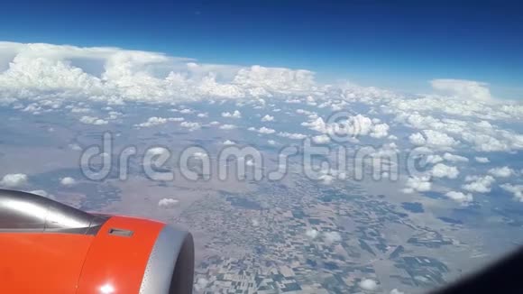 从飞机窗口到蓝天和白云的视野飞机机翼上的一个橙色涡轮机可以看到视频的预览图