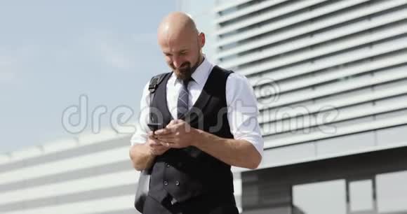 人在城市智能手机上使用商务应用程序英俊的年轻商人在智能手机上微笑交流视频的预览图