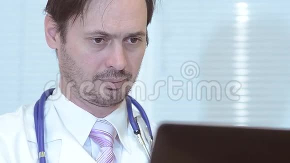 男医生在办公室工作的笔记本电脑特写视频的预览图