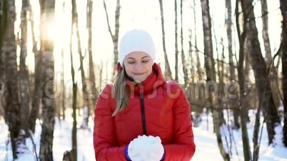 迷人的年轻女子在阳光明媚的冬季公园玩雪玩得开心微笑慢动作视频的预览图