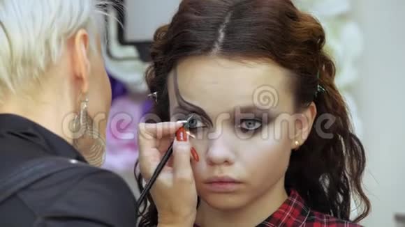 轻松的万圣节化妆美容院的女孩在模型表面应用样式模式设计师的杰作视频的预览图