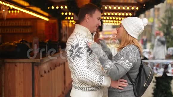 幸福的情侣拥抱在装饰圣诞市场的城市广场上圣诞集市上的美女拥抱男视频的预览图