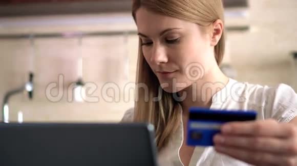 漂亮迷人的年轻女人用笔记本电脑上的信用卡在线购买厨房视频的预览图