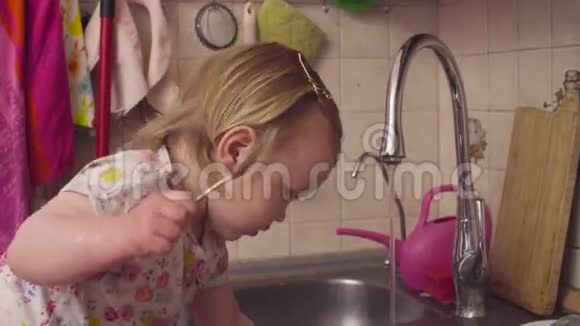 小女孩在厨房水池边玩视频的预览图