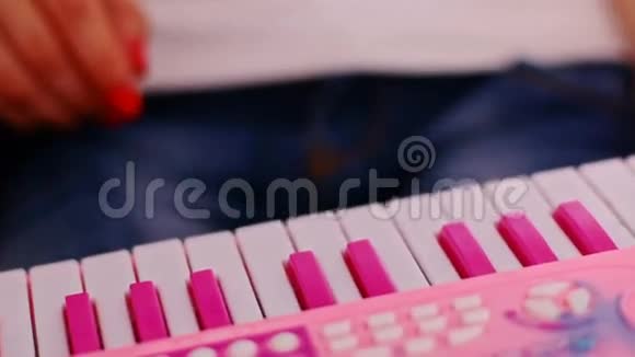 小女孩手指按着粉色玩具钢琴的键视频的预览图