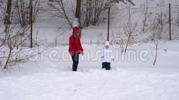 母女俩吐的软鲜雪女人和女孩是欢乐的冬天公园里一个多云的冬天视频的预览图