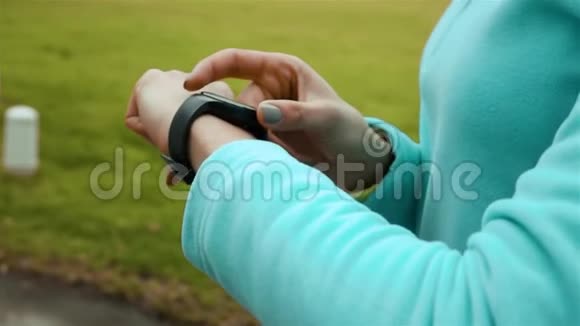 公园里使用智能手表健身追踪器的女跑步者视频的预览图