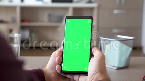 男性手拿着带有绿色屏幕色度的智能手机视频的预览图