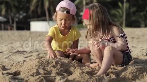 两个可爱的小女孩在沙滩上玩沙子视频的预览图