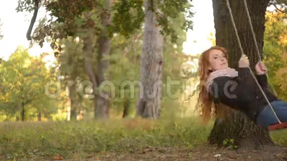 红发女人骑在公园的秋千上视频的预览图