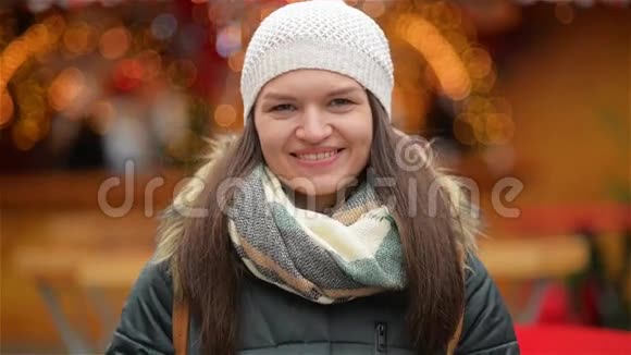 一个穿着温暖衣服的美丽微笑的年轻女人的特写肖像女孩笑着看着镜头视频的预览图