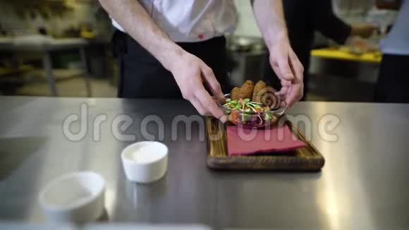 厨师手特写镜头他把酱汁放在木托盘上那里已经有沙拉和蔬菜了视频的预览图