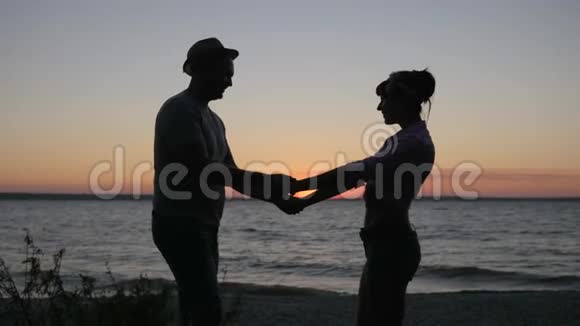 年轻夫妇在夏季海滨度过周末在日落时分亲吻恋人们到海边的河流浪漫的爱情之旅视频的预览图