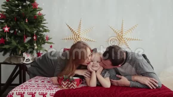 圣诞节早上这个年轻的家庭幸福地互相玩耍在床上放很多枕头圣诞礼物视频的预览图