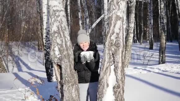 女孩从树后面扔雪冬季景观晴天视频的预览图