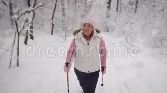 精力充沛的女人穿着温暖的白色背心和黑色裤子在森林里做积极的北欧步行运动女性视频的预览图