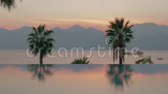 日落时的度假胜地有棕榈海山的游泳池视频的预览图