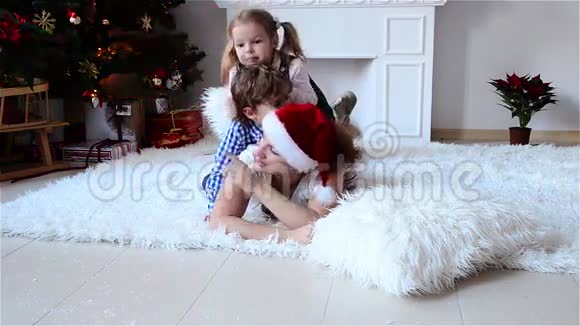妈妈和孩子们在圣诞树附近玩礼物在家过着舒适的冬夜圣诞节新年快乐视频的预览图