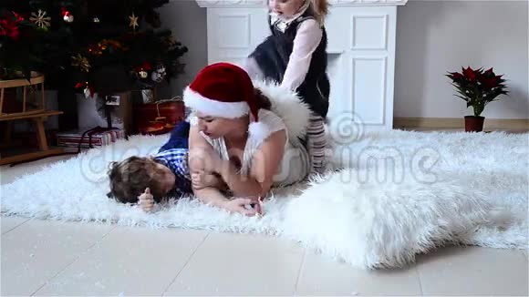 妈妈和孩子们在圣诞树附近玩礼物在家过着舒适的冬夜圣诞节新年快乐视频的预览图