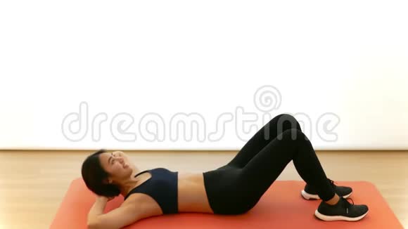 漂亮的泰国亚裔女孩正在做健身节目中的白色背景下的紧身仰卧起坐有氧运动视频的预览图