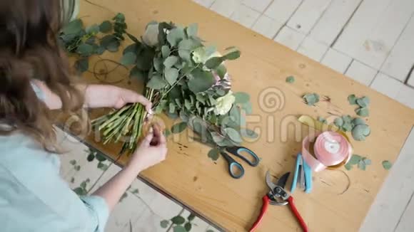 女花艺师在鲜花店制作美丽的花束为婚礼准备佩恩和玫瑰花构图视频的预览图