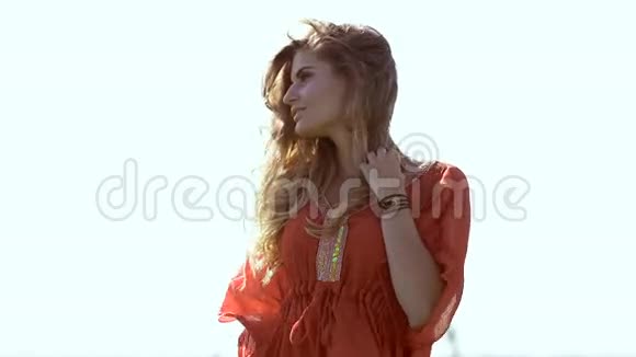 一位美丽的金发年轻浪漫女子穿着红色衬衫站着一副打扮视频的预览图