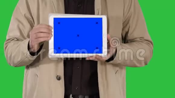 男性手拿平板电脑与蓝色屏幕模型上的绿色屏幕铬键视频的预览图