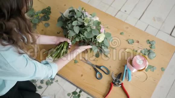 女花匠在鲜花店制作美丽的花束为婚礼准备佩恩和玫瑰花组合视频的预览图