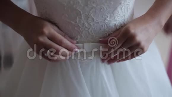 新娘柔软的手在纠正白色婚纱上的蝴蝶结视频的预览图