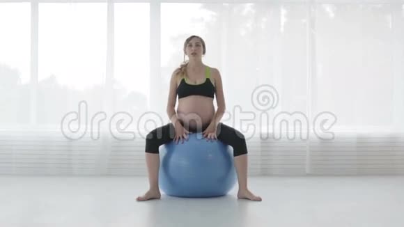 一个大肚子的女孩正在跳蓝色的健身球视频的预览图