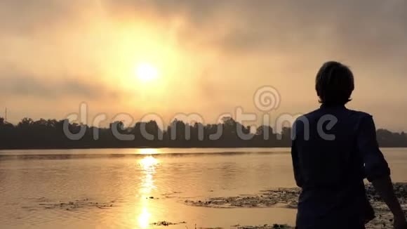 在斯隆莫的一片灿烂的日落中人在一个风景如画的河岸上转过身视频的预览图