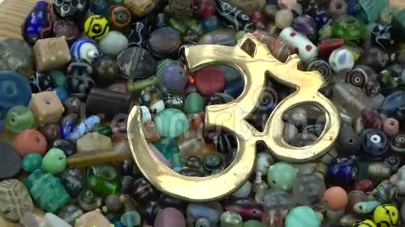 在印度珠子背景上旋转黄铜OM标志视频的预览图