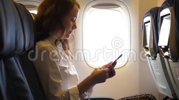 年轻女子在飞机上的智能手机里发短信视频的预览图