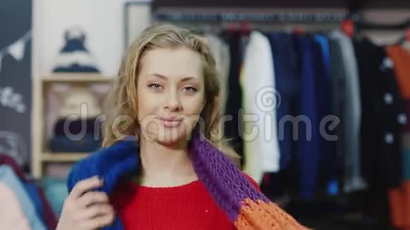 一个戴着围巾的漂亮年轻女子的肖像她站在一家服装店里对着镜头微笑视频的预览图