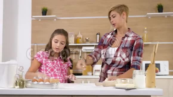 多莉滑块4K镜头母亲和小女儿一起在厨房烘焙和烹饪视频的预览图