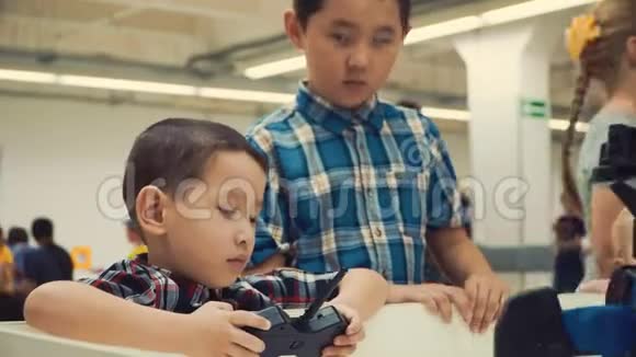 两个亚洲男孩兄弟站在一个人形机器人旁边微笑通过编程方法学习最新的机器人技术是视频的预览图