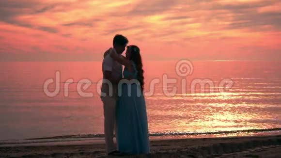 日落时接吻的情侣一对海滩日落吻着剪影爱情夫妻视频的预览图