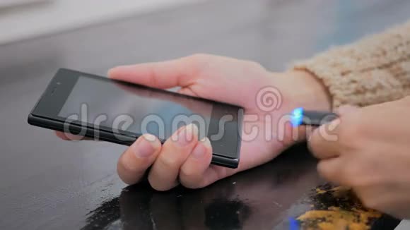 女人手把黑色雷电充电电缆插入智能手机视频的预览图