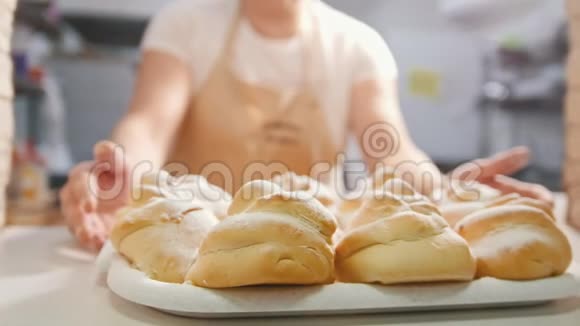 面包店里的厨师端着新鲜的热糕点视频的预览图