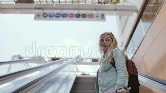 年轻女子在露天购物中心的自动扶梯上移动并手势跟随她视频的预览图