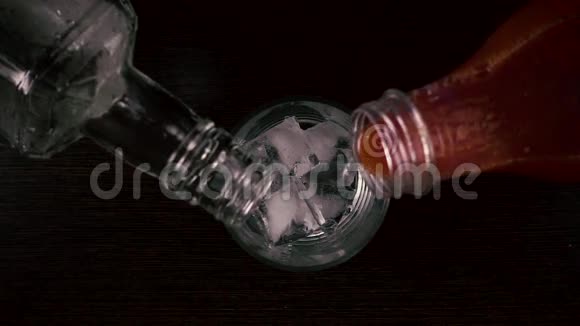 慢动作同时将果汁和伏特加倒入冰顶杯中视频的预览图