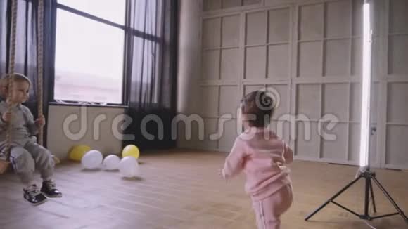 双胞胎姐妹一起玩耍在房子里跑来跑去骑着秋千视频的预览图