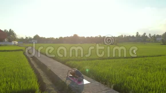 日落时分一位年轻女子在一个美丽的大稻田上练习瑜伽旅游亚洲概念视频的预览图