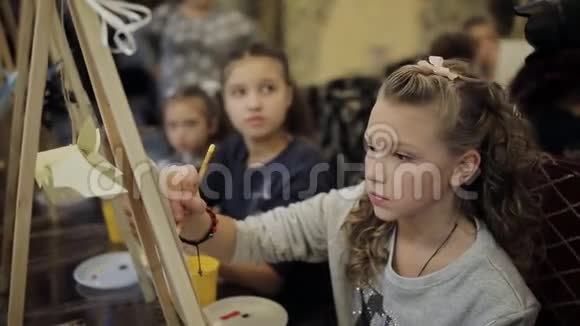 坐在画架上的漂亮少女在一所艺术学校画一幅画儿童专业艺术学校视频的预览图