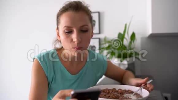 女人吃早餐时用智能手机视频的预览图
