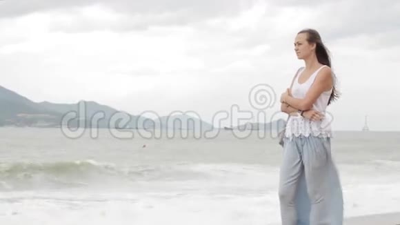 年轻女子站在海滩上天气不好看着大海视频的预览图