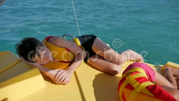 少年睡在海里的船上小男孩坐在一艘游艇上双体船在海里的水面上视频的预览图